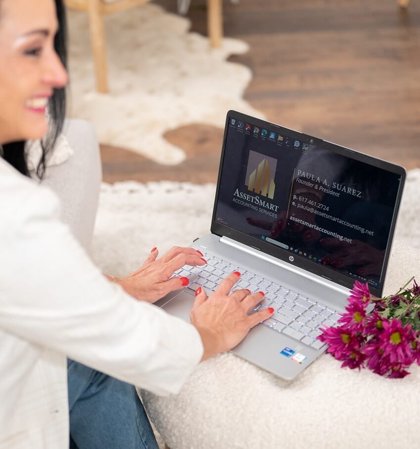 A woman typing on a laptop, with a bouquet of flowers nearby, set in a cozy, modern living room.